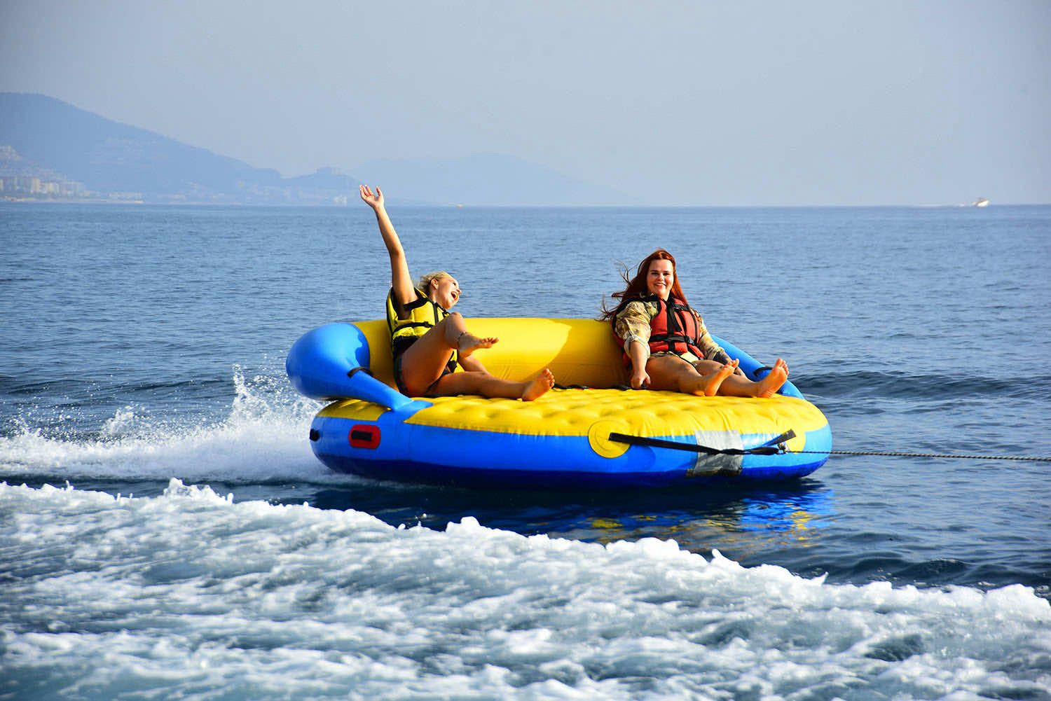 Two guests riding Super Mable inflatable on the sea